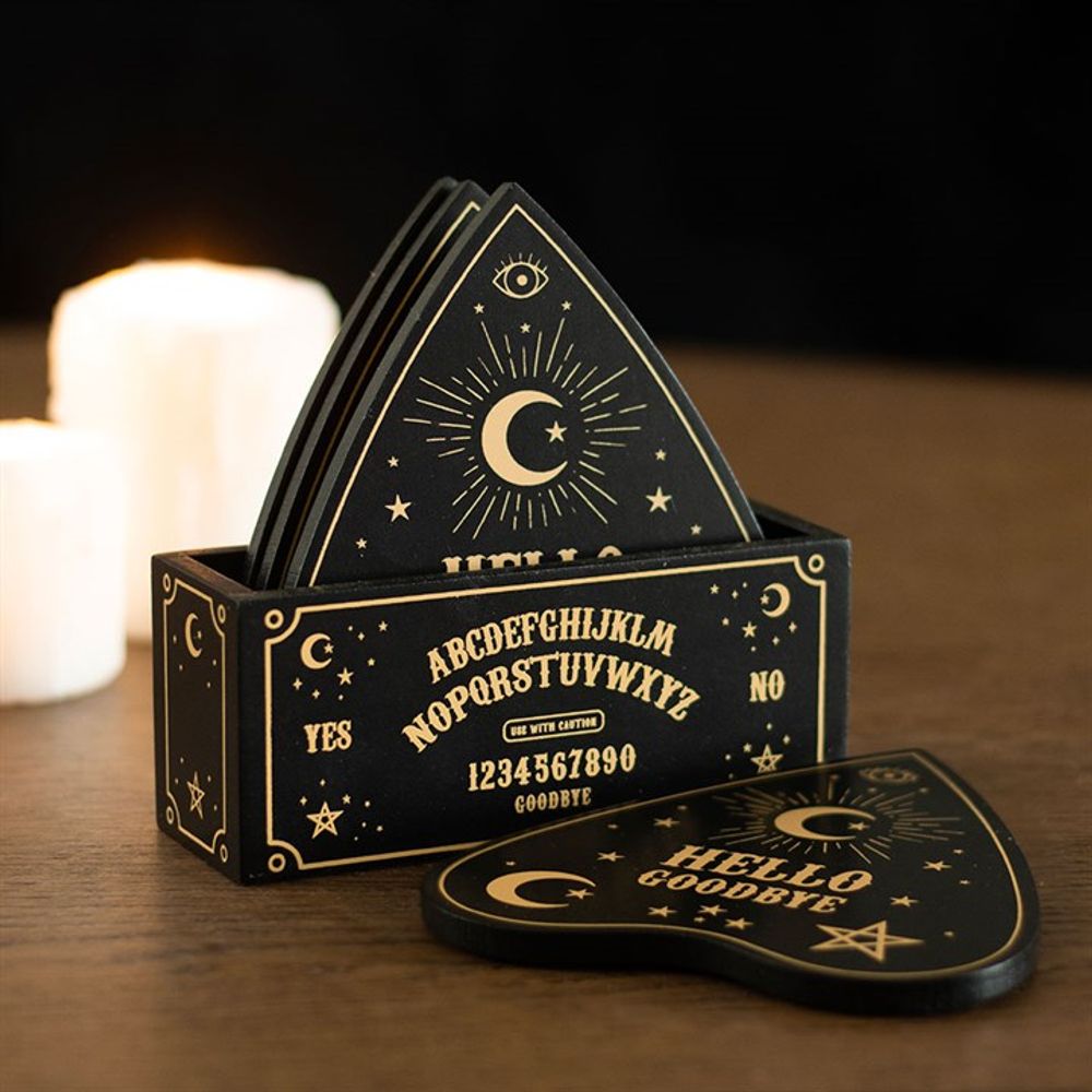a holder holding 3 talking board shaped coasters and one outside the box on the table A talking board is printed on the side of the coaster holder.
