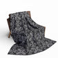 large grey blanket with a black damask gothic style pattern draped over a chair
