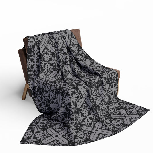 large grey blanket with a black damask gothic style pattern draped over a chair
