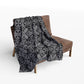 medium grey blanket with a black damask gothic style pattern draped over a chair

