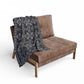 small grey blanket with a black damask gothic style pattern draped over a chair