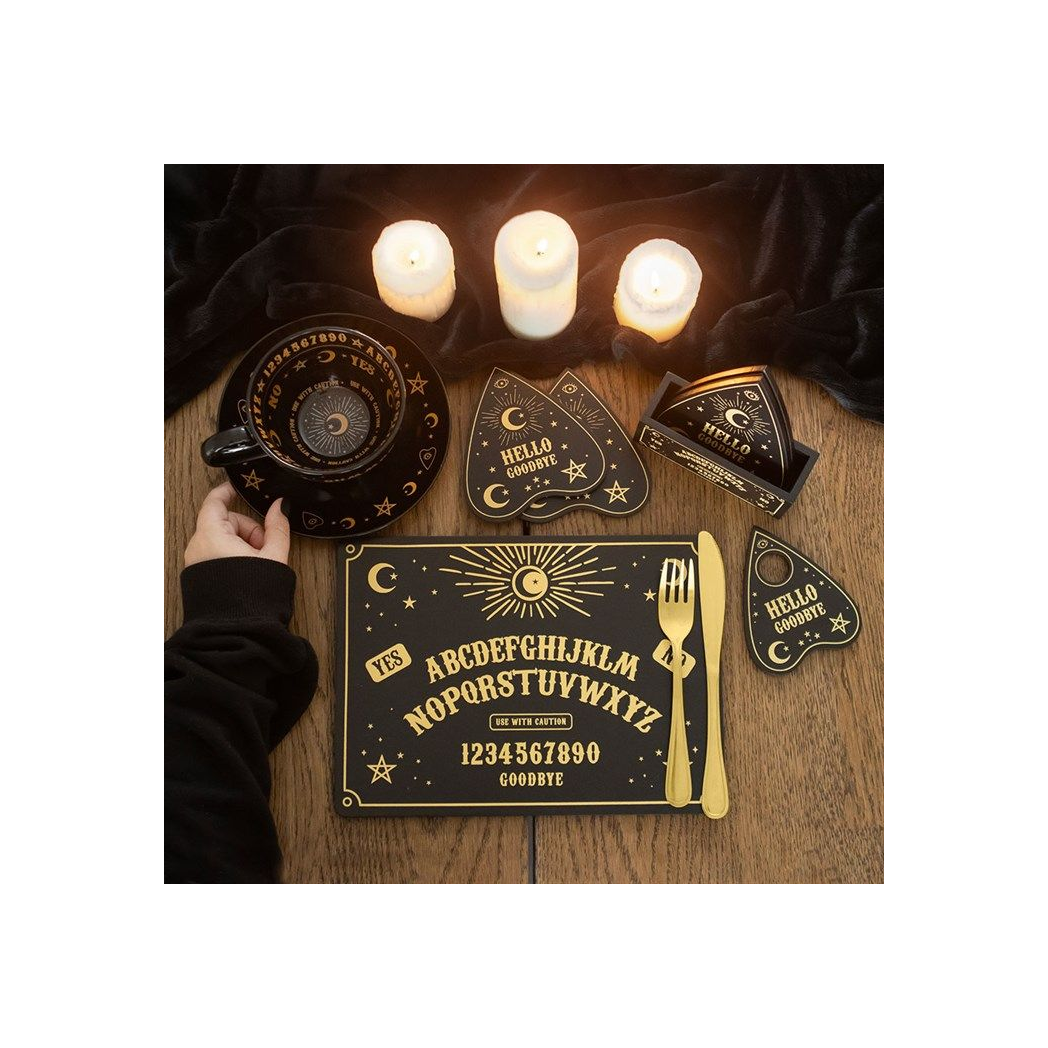 a candlelit table setting with a talking board placemat and coasters along with a cup and saucer