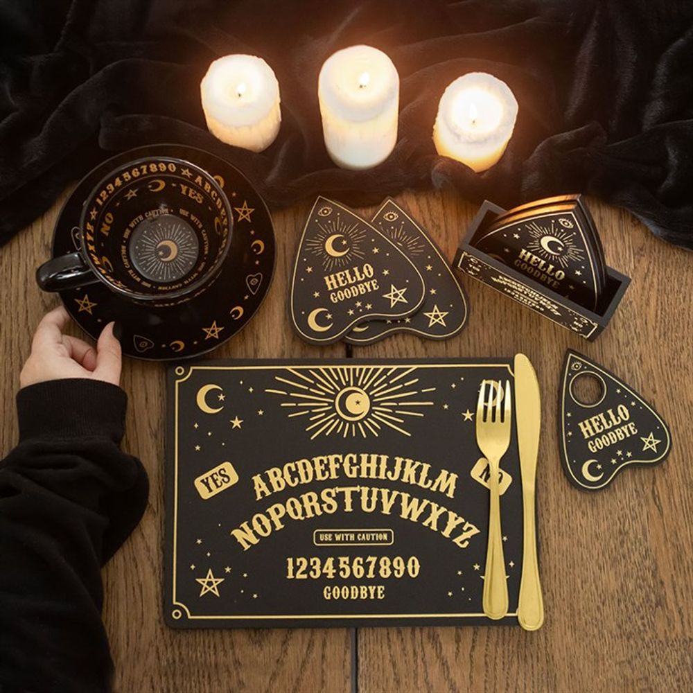 a candlelit table setting with a talking board placemat and coasters along with a cup and saucer