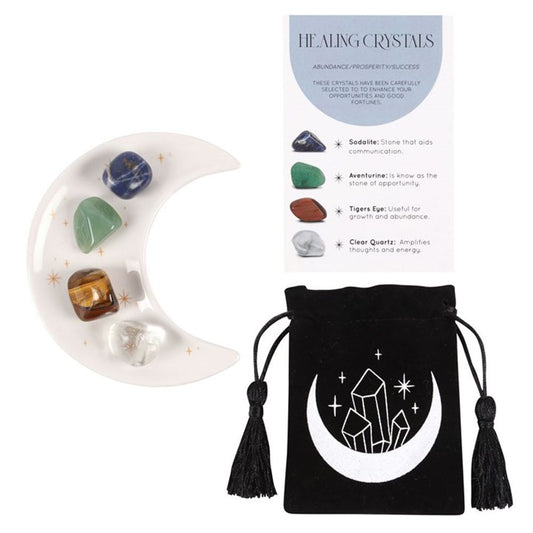 An image of a white half moon trinket dish with golden stars containing each of the 4 crystals available along with the small black velvet pouch with a moon and crystals on it