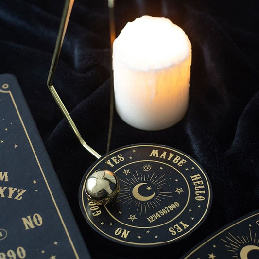 a mystical talking board decision maker with a metal pendulum and a burning candle in the background