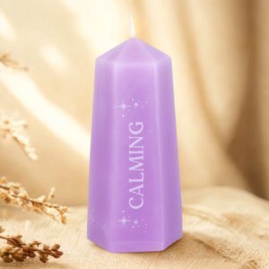 A purple candle on a light wooden surface with soft light in the background