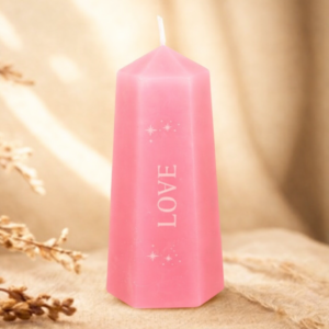 A pink candle on a calm background with the word love inscribed down it's side