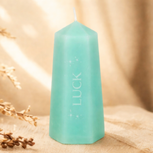 An aqua green candle with the word luck inscribed down the side on a calming background